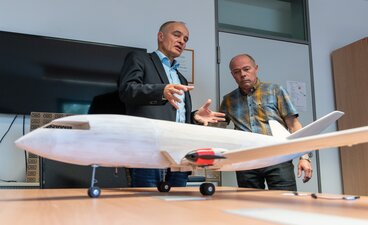 Teaserbild: Zwei Männer begutachten ein Hybridflugzeugmodell
