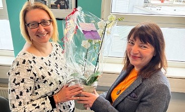 Ivonne Bellen überreicht Simone Karnatz zum Dienstjubiläum eine Orchidee.