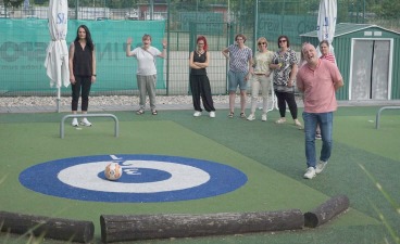 Foto: Mitarbeiterin trifft die Mitte beim Fußball-Curling. Die anderen Mitarbeiter schauen zu. 