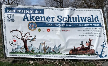 Fotografiert wurde das Banner in Aken, auf dem steht: "Hier entsteht der Akener Schulwald".