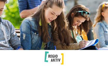 Vier Jugendliche sitzen nebeneinander und schreiben etwas auf Papier. Darunter steht auf einem weißen Streifen das Logo von Regio Aktiv.