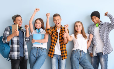 3 Schüler und 2 Schülerinnen in Alltagskleidung stehen nebeneinander und strecken freudig die Arme in die Luft.