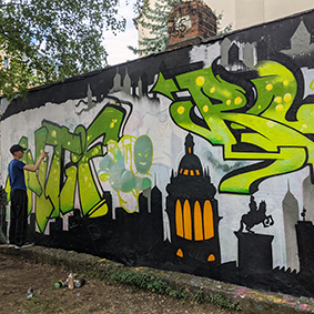 Eine Wand mit grünem Graffiti und einer Person links