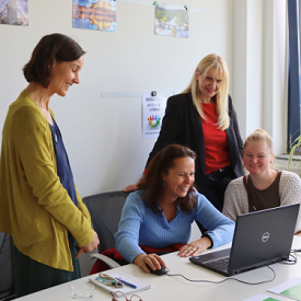 Vier Frauen schauen auf einen Laptop