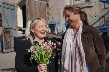 Zwei Frauen mit Blumenstrauß im Hof der Gerüstbaufirma