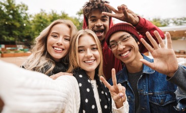 Eine Gruppe Jugendlicher Vier Jugendliche stehen zusammen und lächeln in die Kamera