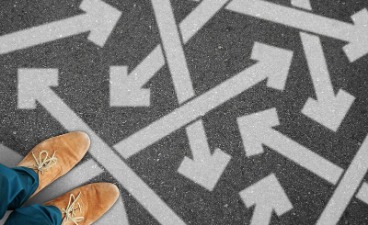 Beispielbild: Foto auf ein Paar braune Schuhe, die auf grauem, mit dicken, weißen Pfeilen versehenen Untergrund stehen. 