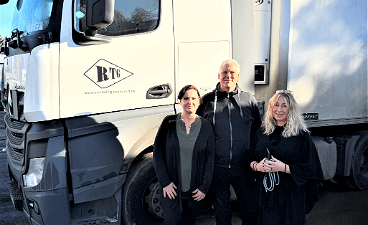 Foto: Drei Personen stehen vor einem weißen LKW.