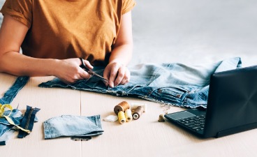   Foto: Eine Frau nimmt an einer Online-Schulung teil und schaut sich einen Nähkurs auf einem Laptop an.