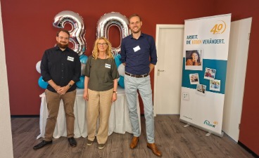 Drei Personen stehen bei der Jubiläumsveranstaltung zum 40-jährigen Bestehen der faw vor einer Ballondekoration mit der Zahl „30“. Von links nach rechts: Christian Hofstadt, stellvertretender Leiter der faw Kaiserslautern, Marion Michel, Standortleitung der faw Kaiserslautern, und Andreas Weber, Geschäftsführer der faw gGmbH.