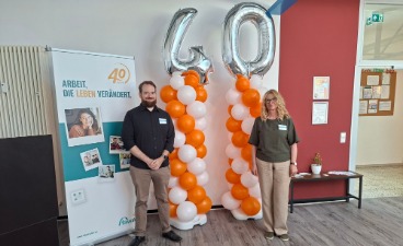 Christian Hofstadt, stellvertretender Leiter der faw Kaiserslautern, und Marion Michel, Standortleitung der faw Kaiserslautern, stehen vor einer Ballondekoration mit der Zahl „40“ und einem Jubiläumsbanner anlässlich des 40-jährigen Bestehens der faw.