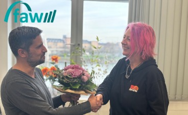 Foto: Jan Scholl-Kaufmann schüttelt Tanja Ueberle die Hand. In der anderen Hand hält er den zu übergebenden Blumenstrauß. 