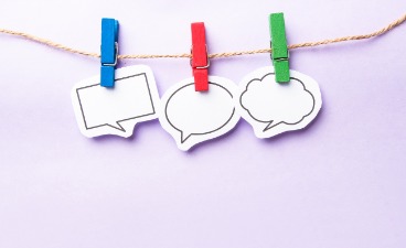Bildhafte Darstellung dreier Sprechblasen, die mit verschiedenfarbigen Klammern an einer Schnur befestigt sind. 