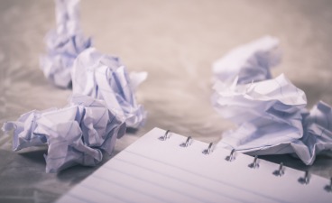 Symbolbild: Schreibblock und zerknülltes Papier