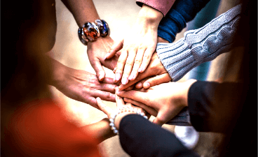 Beispielbild: Sieben Hände, sternförmig übereinander gelegt, von oben fotografiert