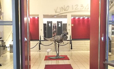 Teaserbild: Nachbau eines Dinosauriers steht im Foyer eines Kinos