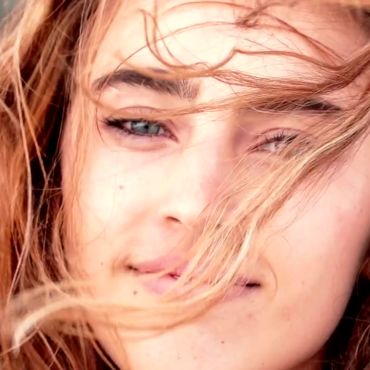 Beispielbild Großaufnahme Kopf: Frau mit Wind in den Haaren lächelt freundlich in die Kamera.