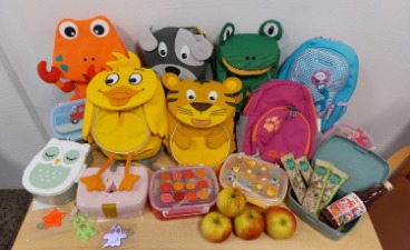 Teaserbild: Bunte Kindergarten-Rucksäcke mit Snackboxen, Obstriegel und Äpfeln