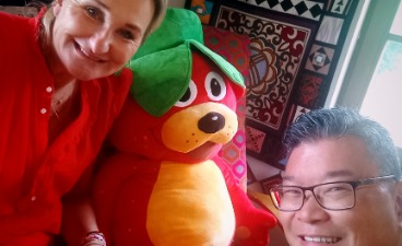 Foto: Selfie von Ulrike Dahl, Heiko Frerichs und mittig dem Maskottchen der Fa. Karls Markt OHG, ein bärenähnliches, rot-gelbes Stofftier mit grünem Blätterhut.