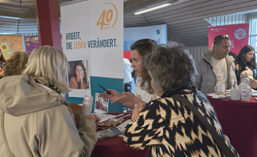 Foto: Besucher*innen beim Informationsaustausch am Messestand der faw.  