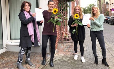 Vier Frauen vor dem Gebäude der FAW, Sonnenblumen und Zertifikate werden übergeben