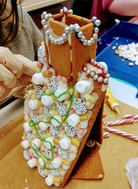 Inhaltsbild: Ein Mädchen verziert ein Lebkuchenhaus mit bunten Süßigkeiten