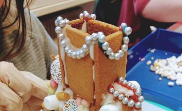 Teaserbild: Ein Lebkuchenhaus wird mit bunten Süßigkeiten verziert