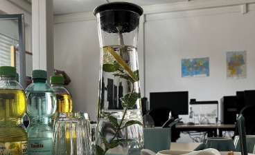 Ein Tisch mit Getränken und Flyern ist zu sehen. 