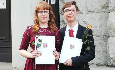 Junge Frau und junger Mann mit Abitur-Zeugnis und Rose in der Hand.