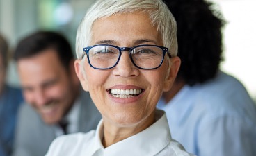 Teaserbild: Frau mit Brille, dahinter fünf Personen im Gespräch