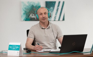 Ein Mann mit Kopfhörer sitzt vor seinem Laptop am Schreibtisch. 